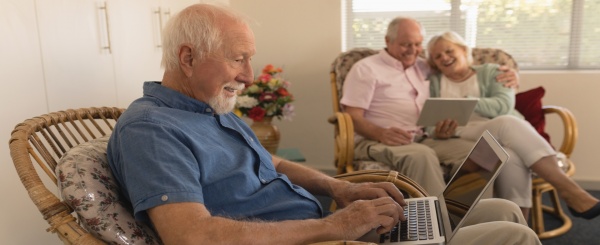 senior man using laptop while senior couple using NZPB57D 2